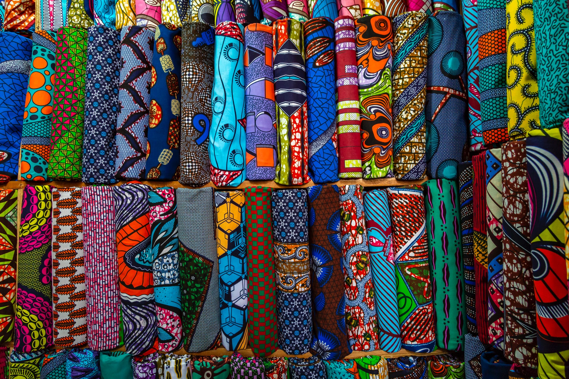 Diverse and colourful fabrics in a market. Photo by Eva Blue, Unsplash
