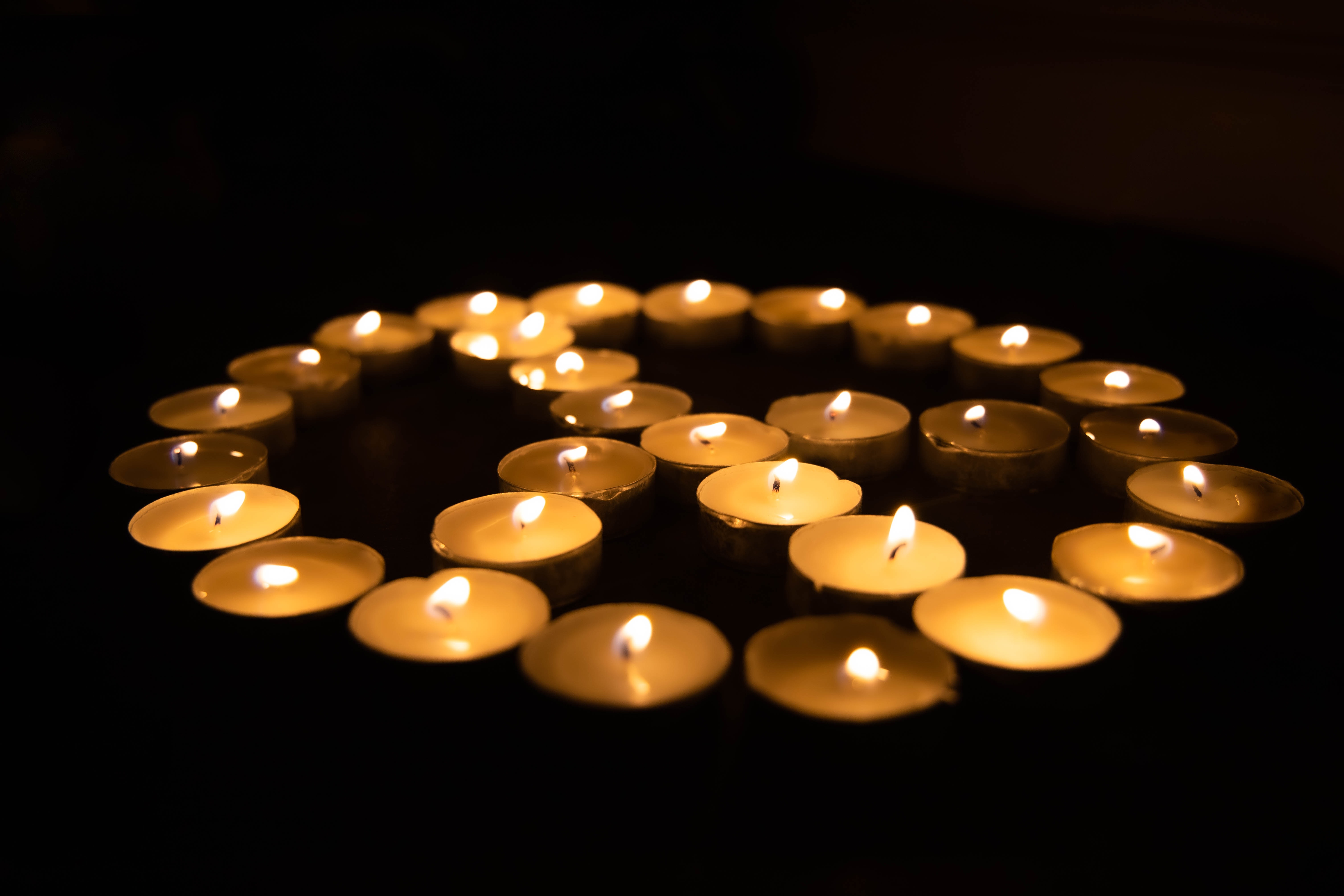A circle of tea lights forming the sign of peace. Photo by Joshua Sukoff, Unsplash.